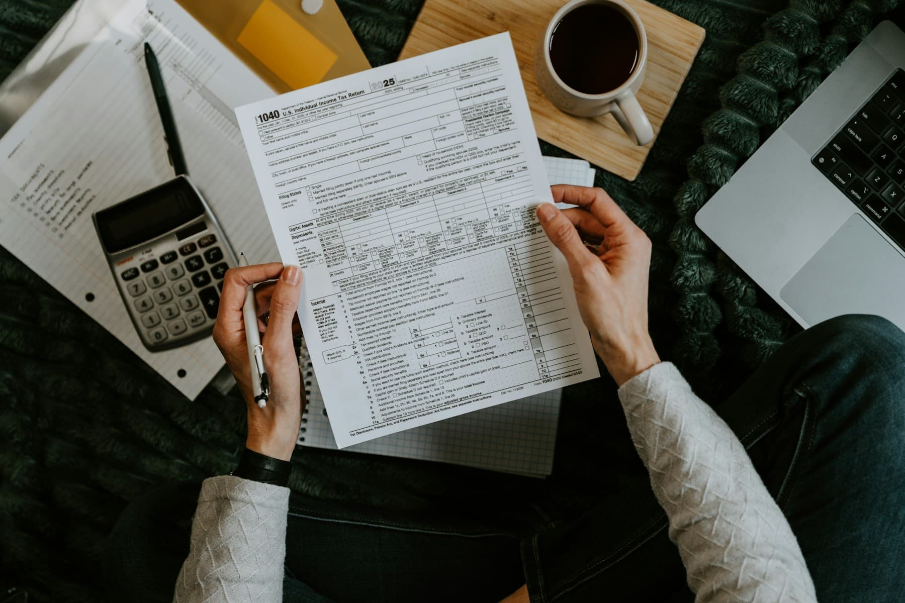 Taxpayer reviewing a Form 1040 with a calculator and laptop